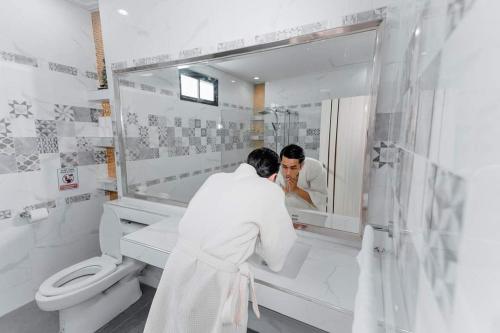 Een man in een badkamer die in de spiegel kijkt. bij 69YIng Yang House 3BR Sawankhalok in Sawankhalok