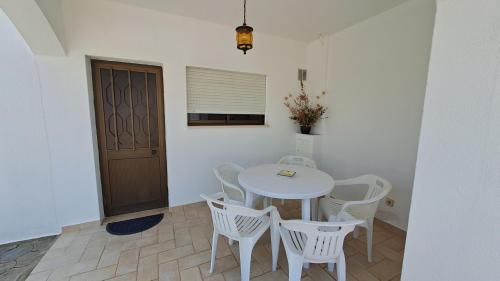 a dining room with a table and white chairs at Albufeira Traditional Apartments IN VILLA in Albufeira