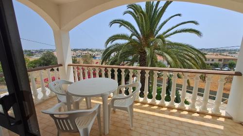 a balcony with a table and chairs and a palm tree at Albufeira Traditional Apartments IN VILLA in Albufeira