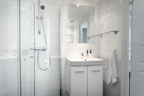 uma casa de banho branca com um chuveiro e um lavatório. em Frogner House - Oscars gate em Oslo