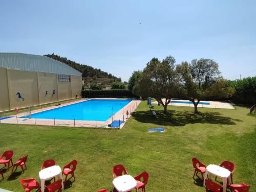 a view of a pool with red chairs and a pool at Casa Rural La Gineta in Calaceite