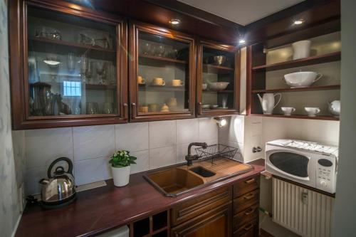 a kitchen with wooden cabinets and a sink and a microwave at Studio by the Beach in Gdańsk