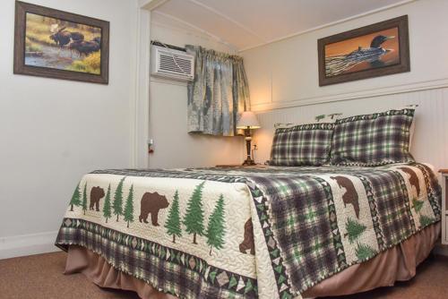 Un dormitorio con una cama con una manta con animales. en Adirondack Sunrise Lodge, en Lake George