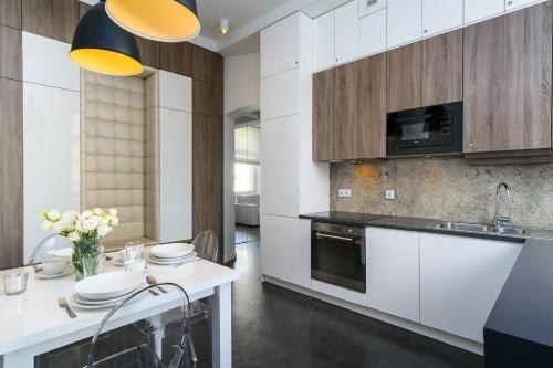 ソポトにあるElite Apartments Sopot Premiumのキッチン(白いキャビネット、テーブル、椅子付)