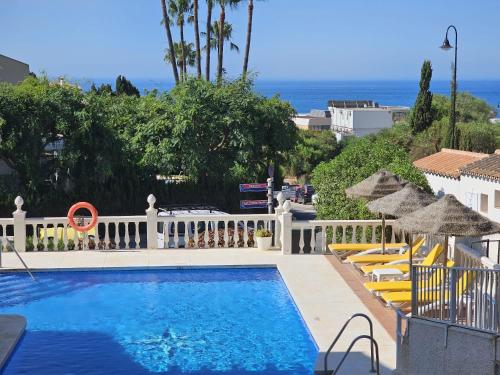 a swimming pool with umbrellas and chairs and the ocean at Apartamento SEA VIEW Celeste Costa del sol Playa Chapparal in Mijas Costa