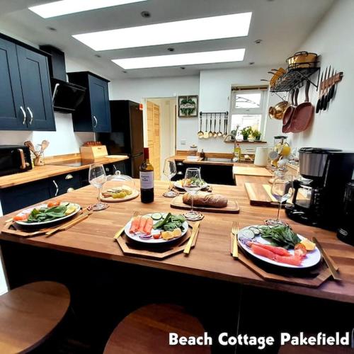 a kitchen counter with plates of food and wine glasses at Beach Cottage Pakefield- Newly Fully Renovated House in Pakefield