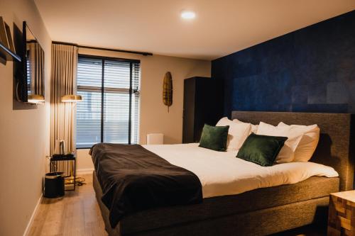 a bedroom with a large bed with green pillows at City Hotel de Jonge in Assen