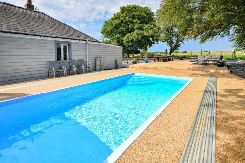 a blue swimming pool with a bench next to a house at The Ynys Lodge in Pwllheli