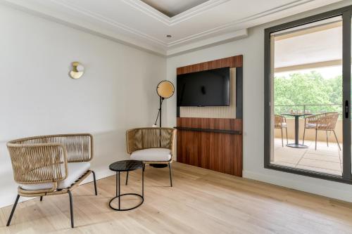 a living room with chairs and a flat screen tv at Zenitude Hotel la Valadière, an Ascend Collection Hotel in Montpellier