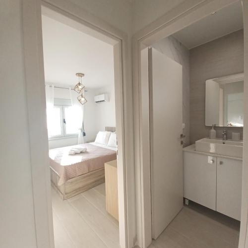 a white bedroom with a bed and a sink at Ionian Avra Apartment in Athani