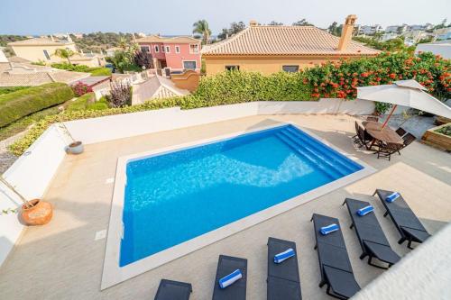 uma piscina com cadeiras e um guarda-sol numa casa em Casa Talay 4 Bedroom Pool Villa - Meia Praia Beach, Lagos em Lagos