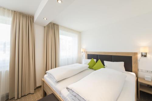 a bedroom with a large bed with white sheets and green pillows at Apartment Paula in Seefeld in Tirol