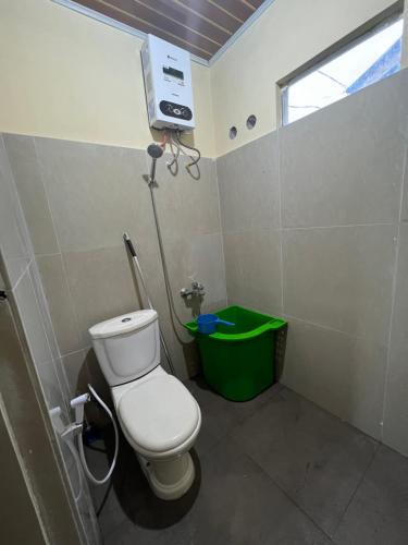 baño con aseo y cubo de basura verde en Ulina Villa Segitiga Berastagi en Berastagi