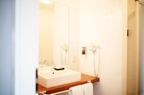 a white bathroom with a sink and a shower at Hotel Dieksee - Collection by Ligula in Malente