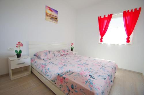 a bedroom with a bed and a window with red curtains at Holiday apartment Silvija, Loborika in Loborika