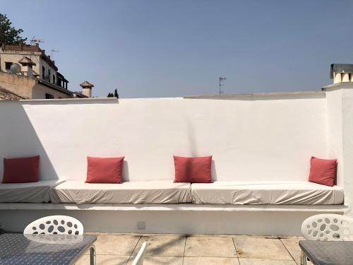 a white bench with red pillows on a rooftop at Amazing Loft! Rooftop Terrace! Alhambra Views! in Granada