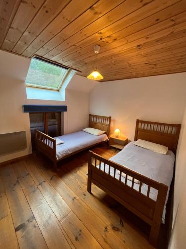 2 Betten in einem Zimmer mit Holzböden und einem Fenster in der Unterkunft Townhouse The Granary Bourg d’Oisans in Le Bourg-dʼOisans