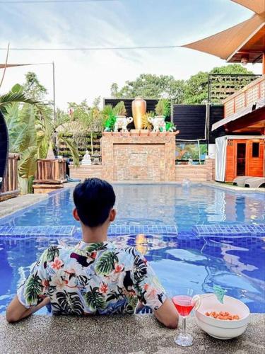 a young boy sitting next to a pool with a bowl of food and a drink at Delia's Guest House in Mactan