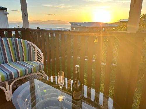 a bottle of wine and a glass on a table on a balcony at The Lazy Fig - Ocean Views, Orchard & Pizza Oven in Primrose Sands