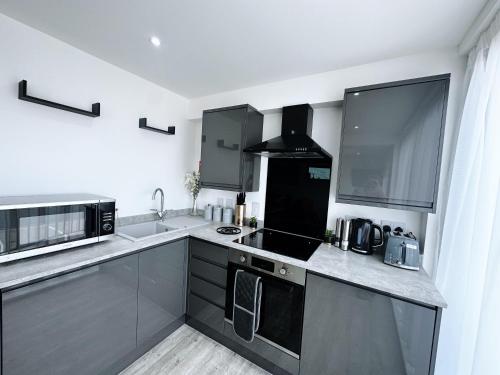 a kitchen with gray cabinets and a stove top oven at The Atlantis - Tower Apartments in Great Yarmouth