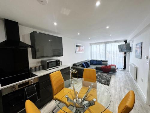 a living room with a glass table and yellow chairs at The Atlantis - Tower Apartments in Great Yarmouth