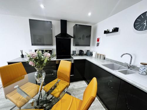 a kitchen with a glass table and yellow chairs at The Atlantis - Tower Apartments in Great Yarmouth