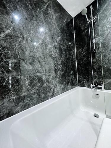 a white bath tub in a bathroom with black marble walls at The Atlantis - Tower Apartments in Great Yarmouth