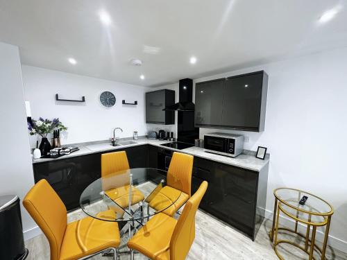a kitchen with a glass table and yellow chairs at The Atlantis - Tower Apartments in Great Yarmouth