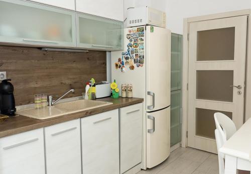 cocina con armarios blancos y nevera en Chayka Charm Cozy 1BD Apartment in Varna, en Varna