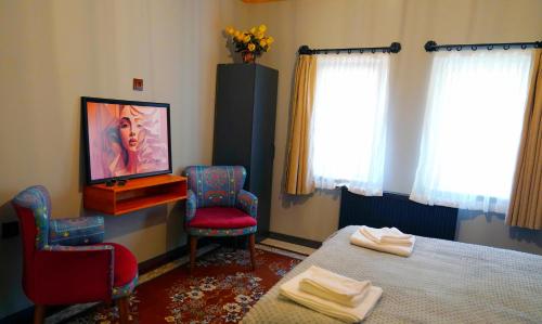 a bedroom with a bed and two chairs and a television at Alpha Stone House in Goreme
