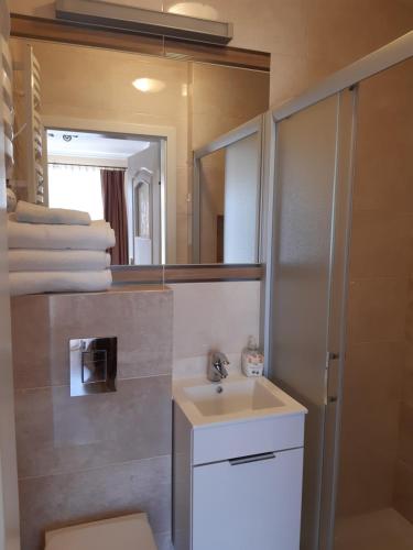ein Bad mit einem Waschbecken und einem Spiegel in der Unterkunft Bumerang pokoje gościnne in Ustronie Morskie