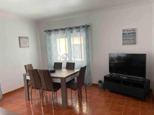 a dining room with a table and chairs and a television at Apartamento Bella Vista São Martinho do Porto in São Martinho do Porto
