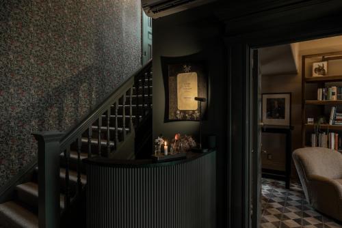 a hallway with a staircase with a chair and a book shelf at Dvele Inn in St. John's