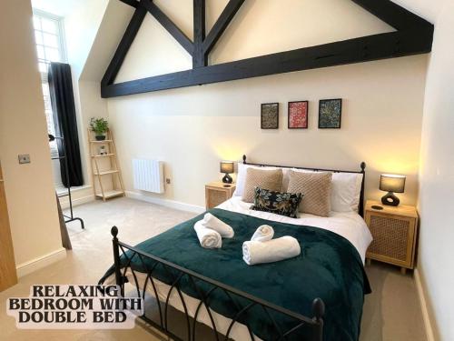 a bedroom with a bed with two swans pillows on it at Brand New! Stunning, Stylish, Cosy Apartment in Centre of Saffron Walden in Saffron Walden