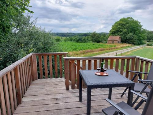 a wooden deck with a table with a bottle of wine on it at La Bucolique de Tahier in Ohey