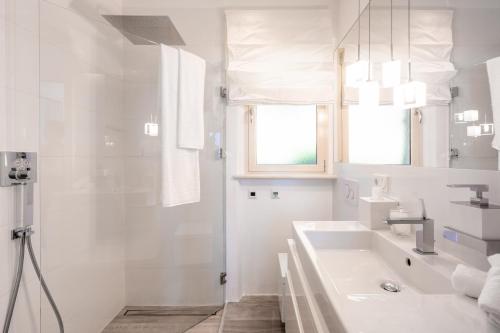 ein weißes Bad mit einem Waschbecken und einer Dusche in der Unterkunft Apartment Wieser Garda Lake in Gargnano