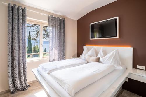 ein weißes Bett in einem Schlafzimmer mit einem Fenster in der Unterkunft Apartment Wieser Garda Lake in Gargnano