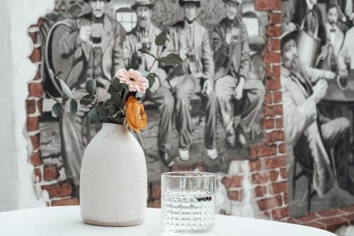 a white vase with flowers and a glass on a table at Layer Residences in Kranj