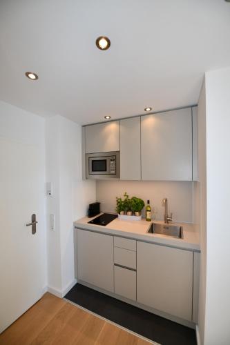 eine Küche mit weißen Schränken und einem Waschbecken in der Unterkunft Glück Auf Appartements Hillerstraße Köln in Köln