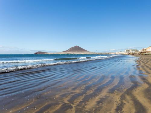 a sandy beach with waves in the ocean at Live Medano Casanova frente a la playa in El Médano