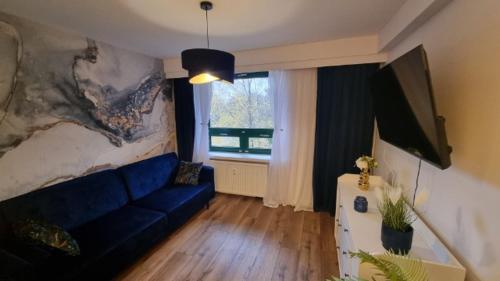 a living room with a blue couch and a window at Apartament nad zalewem 217 in Serock