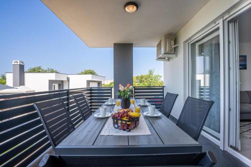 a wooden table with a bowl of fruit on a balcony at Domus Alba Apartments in Pula