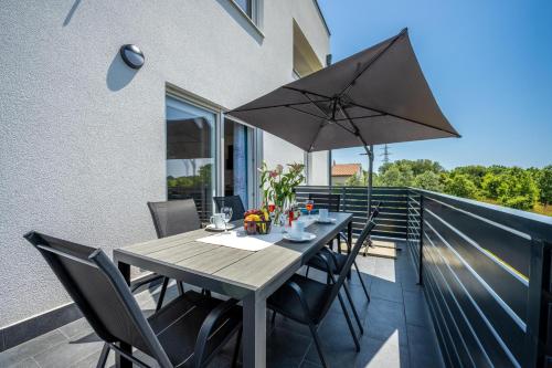 a wooden table with chairs and an umbrella on a balcony at Domus Alba Apartments in Pula