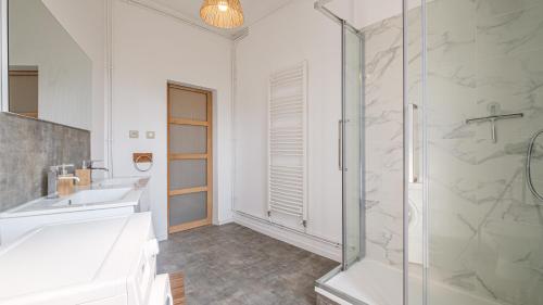 uma casa de banho branca com um chuveiro e um lavatório. em Les Cheminées - Welc'Home em Limoges