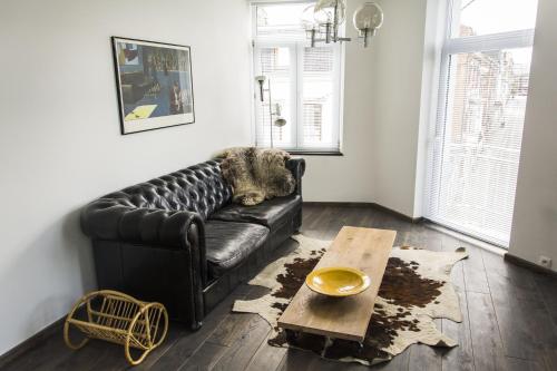 a black leather couch in a living room with a table at Entre Deux Pays Apartments in Spa