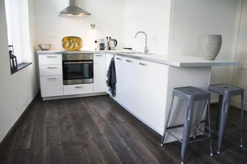 a kitchen with white appliances and a wooden floor at Entre Deux Pays Apartments in Spa