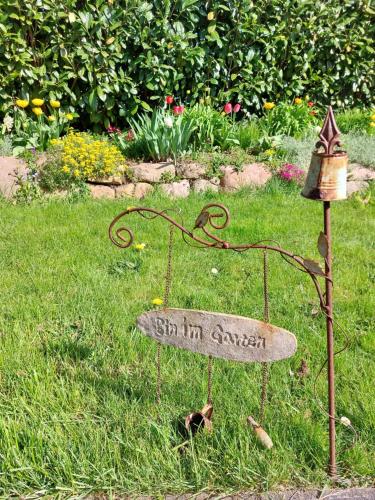 a sign in a garden with a birdbath in the grass at Klosterblick in Bad Doberan