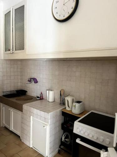 - une cuisine avec une horloge sur le mur au-dessus d'une cuisinière dans l'établissement Le Pêcheur, à Cassis