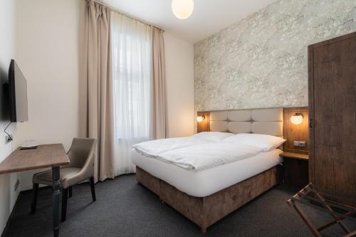 a hotel room with a bed and a desk and a window at EA Hotel Victoria in Prague