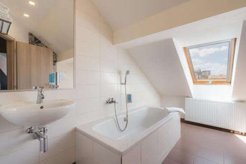 uma casa de banho branca com um lavatório e uma banheira em EA Hotel Victoria em Praga